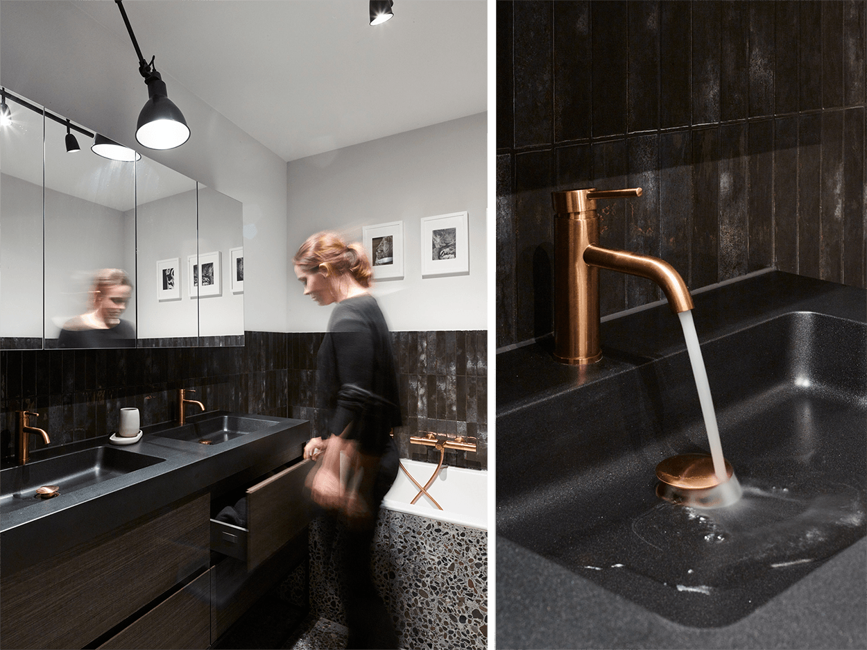 Nahaufnahme einer kupferfarbenen Waschtischarmatur in einem industriellen Badezimmer von x²o Badezimmer, montiert auf einer schwarzen Waschtischplatte mit integriertem Becken.