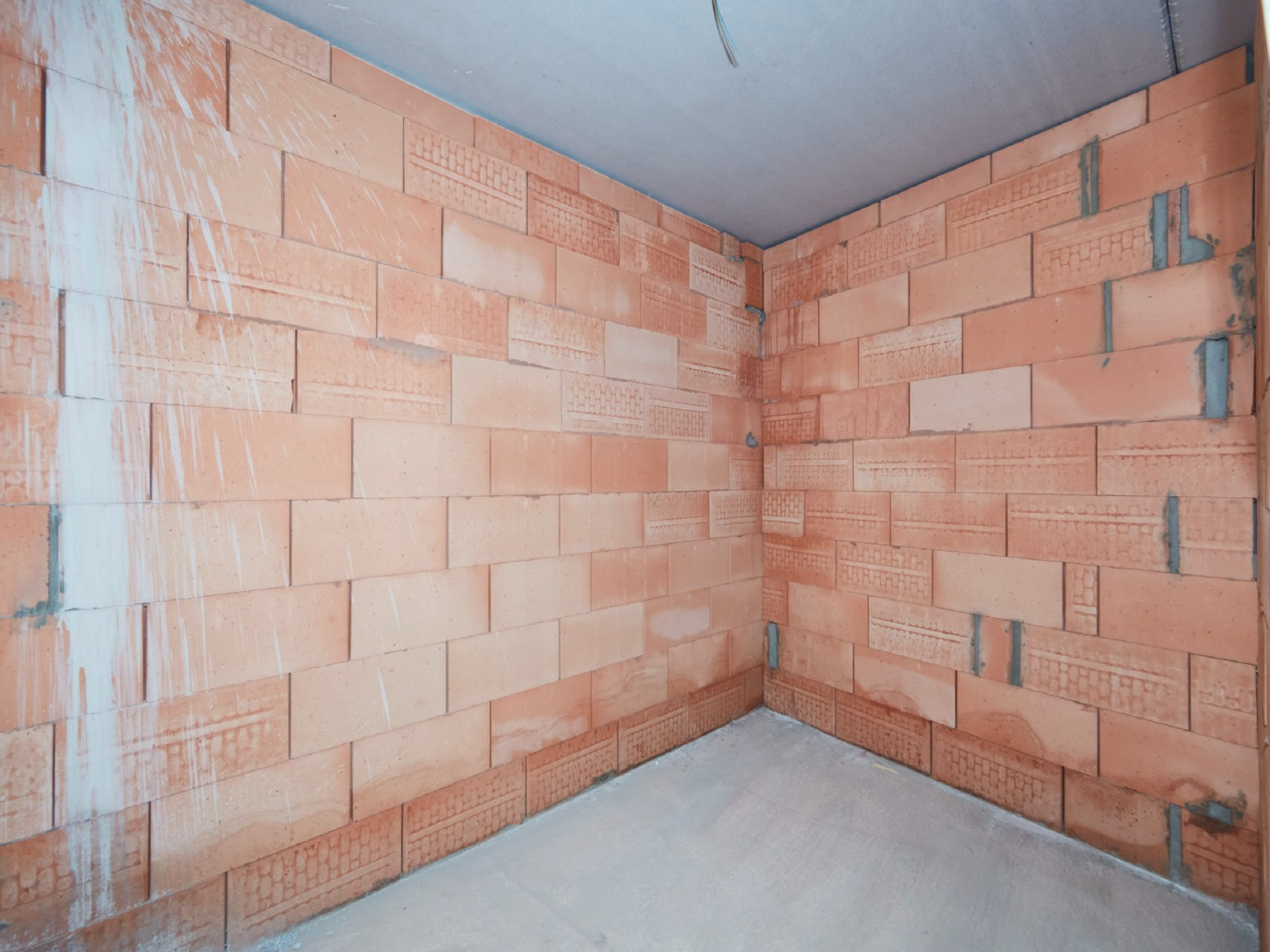 Industrielles Badezimmer von x²o Badezimmer mit Doppelwaschtisch, kupferfarbenen Armaturen, Terrazzo-Badverkleidung und dunklen Fliesen für eine robuste Optik.