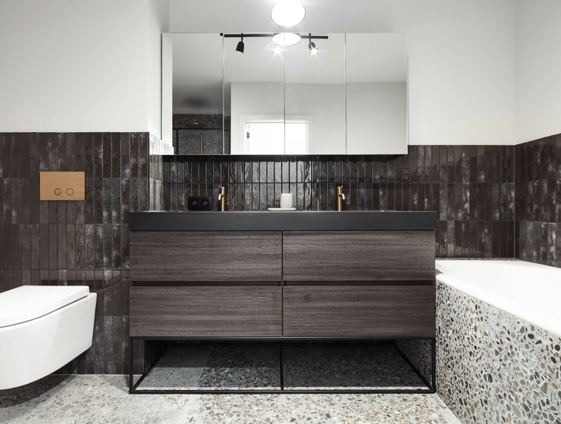 Moderne industrielle Badezimmergestaltung von x²o Badezimmer mit einem Doppelwaschtisch aus dunklem Holz, einer schwarzen Waschtischplatte mit zwei integrierten Becken, kupferfarbenen Armaturen, dunklen Wandfliesen und einem großen Spiegelschrank darüber.