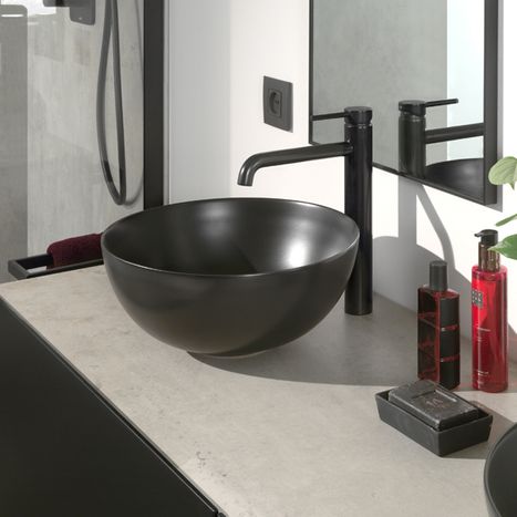 Dunkles integriertes Waschbecken in einem Badmöbel mit Holzfronten, mit Chromarmatur und Pflanze, aus dem x²o Badezimmer-assortiment.