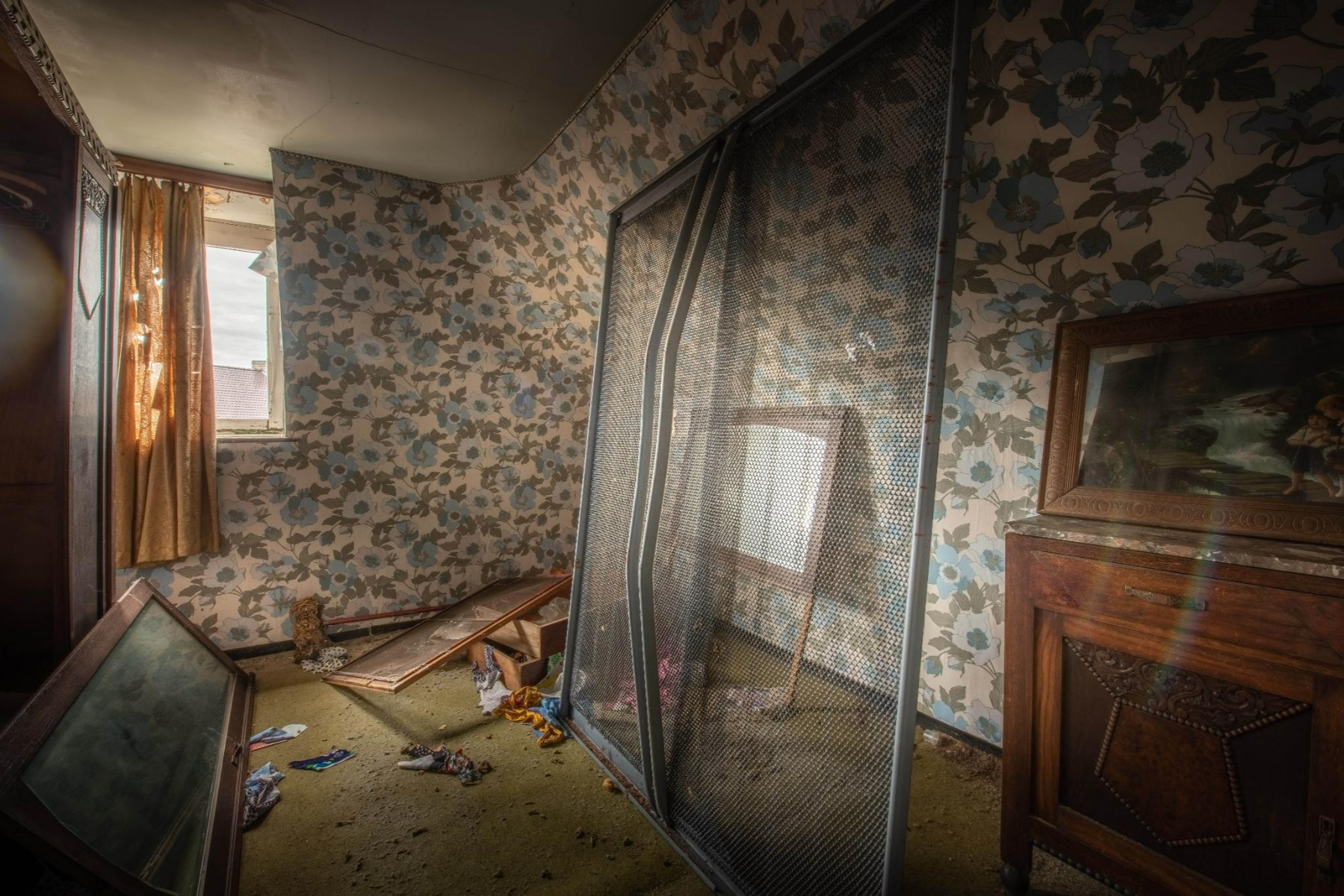 Vor der Renovierung zeigt x²o Badezimmer einen stark veralteten Raum mit Blumentapete, beschädigten Holzmöbeln, losen Fensterrahmen und einer dunklen, unaufgeräumten Atmosphäre.