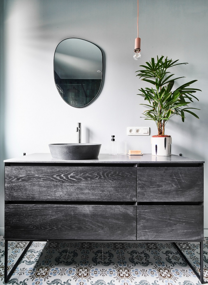 Waschtischunterschrank von x²o Badezimmer in dunkler Holzoptik mit integrierten Schubladen, kombiniert mit einer klaren Waschtischplatte und moderner Armatur.