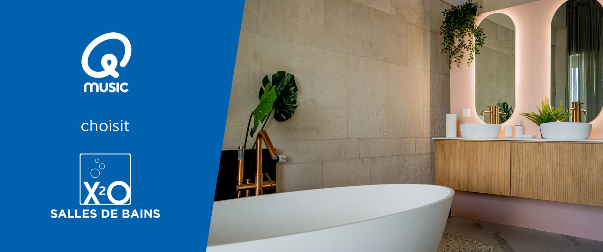 Salle de bains moderne et luxueuse avec une baignoire îlot blanche, un meuble de salle de bains en bois chaleureux et des miroirs arrondis avec éclairage indirect doux. Les robinetteries dorées et les plantes vertes créent une ambiance élégante dans cet aménagement x²o salles de bains.