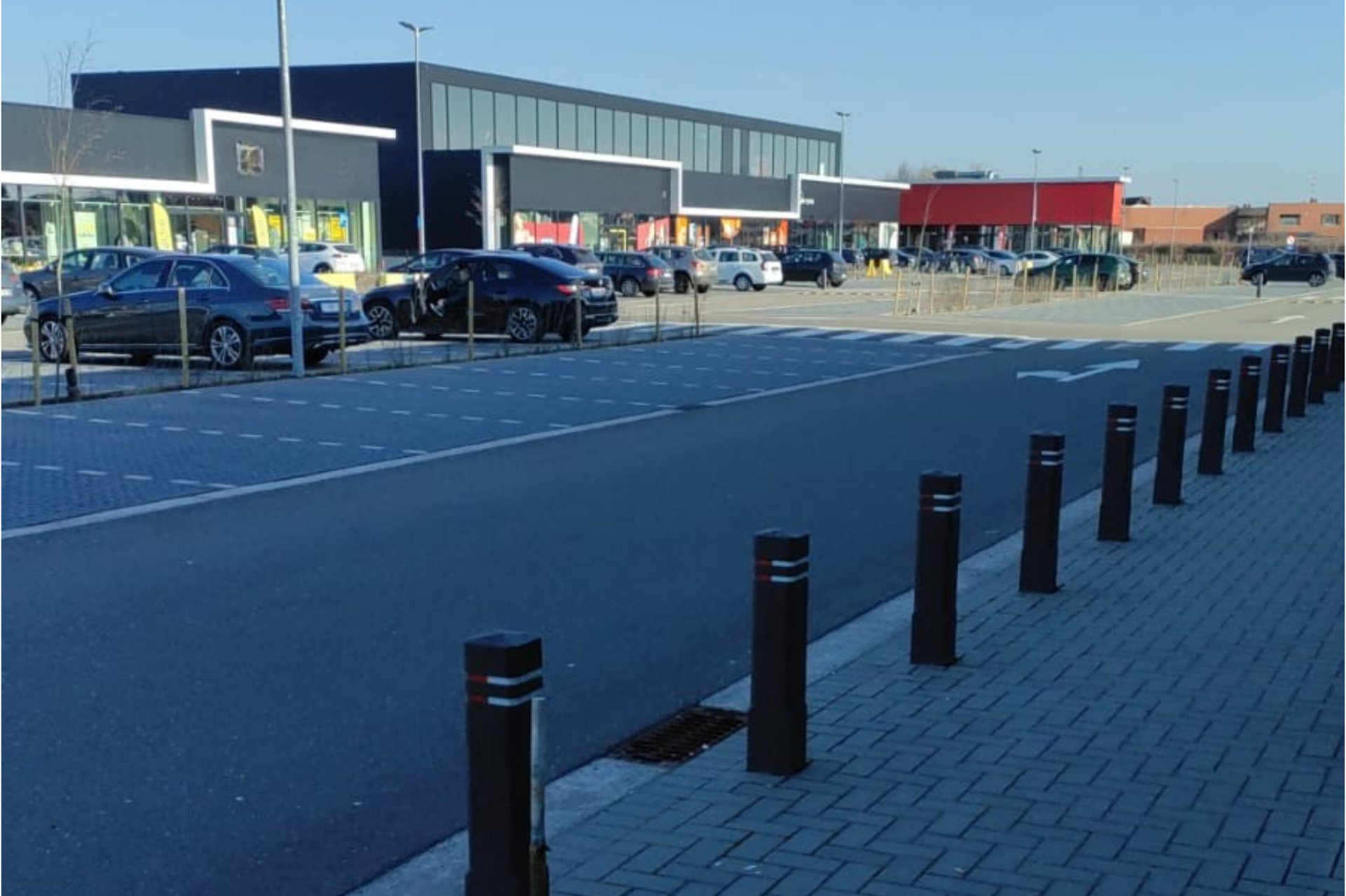 Parking x²o salles de bains à Bree avec plusieurs voitures et accès au showroom en arrière-plan.