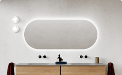 Du siehst ein Badezimmermöbel von x²o Bad mit einem ovalen Spiegel und umlaufender indirekter LED-Beleuchtung. Darunter befindet sich ein Holzwaschtisch mit schwarzen Armaturen vor einer hellen Wand.