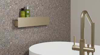 Étagère murale dorée X²O avec produits de soin au-dessus d’une baignoire.