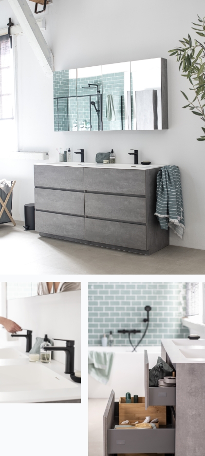 Meuble de salle de bain en béton avec miroir, robinets noirs et tiroir avec objets de rangement, carreaux verts au mur.