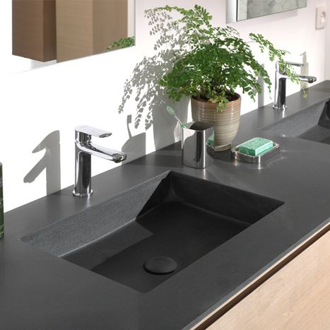 Donkere rechthoekige wastafel geïntegreerd in een strak werkblad met chromen kraan, met open lade en accessoires, in een badkamer van x²o badkamers.