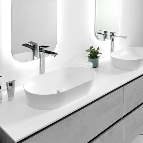 Moderne witte waskom met afgeronde rand op een licht meubel, gecombineerd met spiegel en badkameraccessoires, opgesteld in een x²o badkamers interieur.