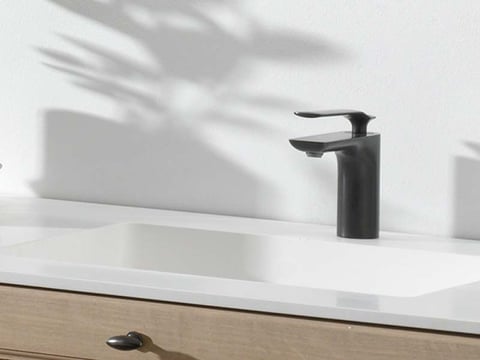 Wastafel met wit blad en minimalistische zwarte kraan op een houten meubel.