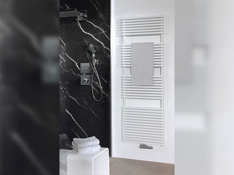 Badkamer met zwarte marmeren douchewand, moderne douchekraan en witte handdoekradiator met handdoek.
