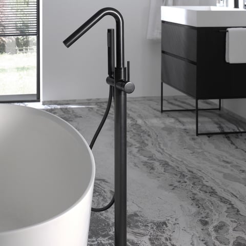Vrijstaande zwarte badkraan met handdouche naast een modern wit ligbad, stijlvol en minimalistisch ontwerp.