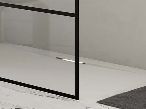Minimalistische inloopdouche met zwart frame en discreet geïntegreerde afvoer in marmeren vloer.