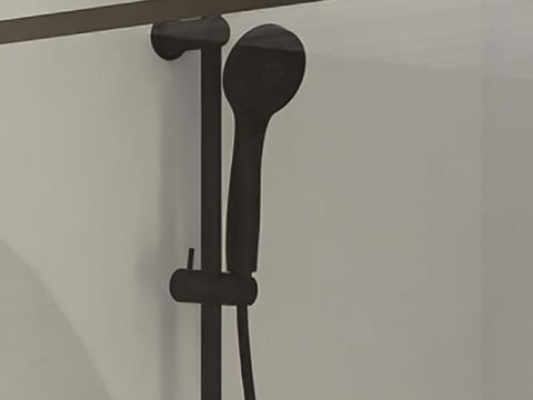 Zwarte handdouche op een verstelbare rail, gemonteerd op een glazen douchewand.