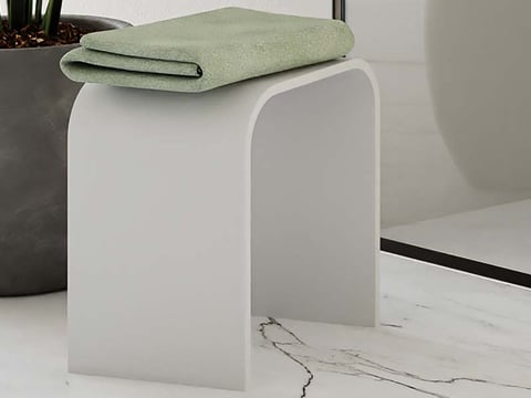 Moderne witte badkamerkruk met afgeronde randen, voorzien van een opgevouwen groene handdoek.