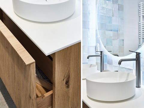 Moderne wastafel met houten meubel en dubbele kranen in badkamer.