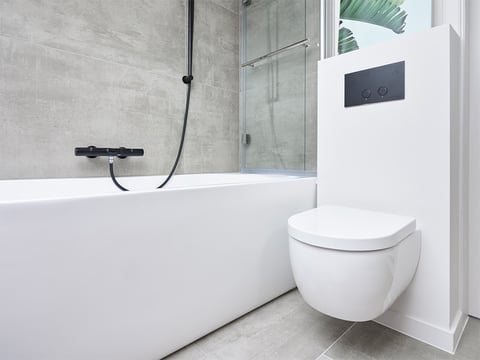 Wit ligbad, zwarte kraan, doucheruimte met glazen wand en een zwevend toilet.