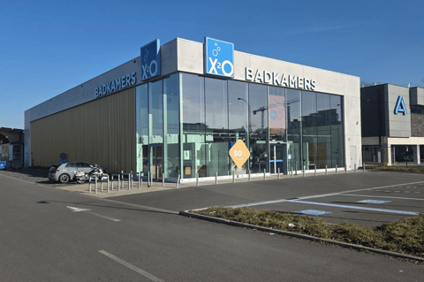 Moderne X²O Badkamers winkel met glazen gevel en ruime parking aan de straatzijde – X²O badkamers