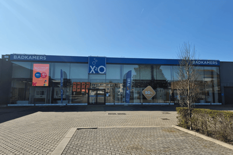 Magasin X²O salles de bains avec large façade vitrée, entrée et parking devant le bâtiment – X²O salles de bains