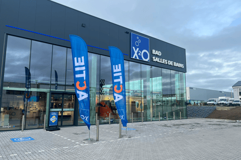 Magasin X²O salles de bains avec façade vitrée et drapeaux promotionnels à l’entrée – X²O salles de bains