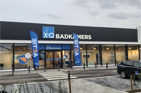Showroom x²o salles de bains à Bree avec enseigne bleue et installations visibles à l’intérieur.