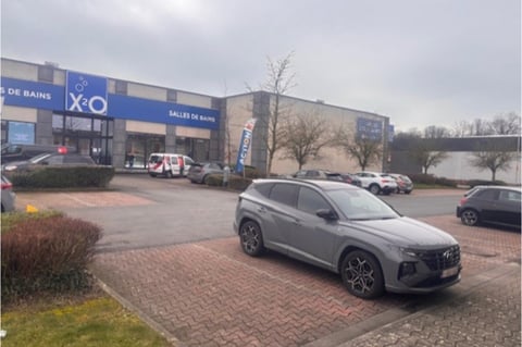 Parking van x²o badkamers in Charleroi met meerdere auto’s en showroom zichtbaar op de achtergrond.