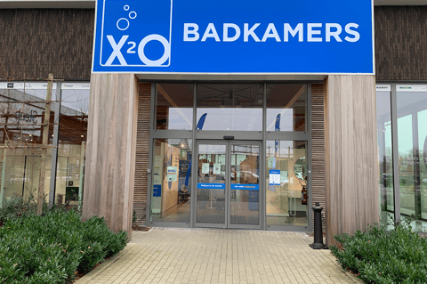 Entrée du showroom X²O salles de bains avec grande signalisation en façade, portes coulissantes automatiques et accès soigné accueillant les clients – X²O salles de bains
