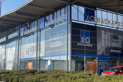 X²O Badkamers showroom met grote glasgevel, banners en ingang in een retailpark – X²O badkamers