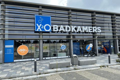 X²O Badkamers winkel met glazen gevel, promotiestickers en ingang aan de straatzijde – X²O badkamers