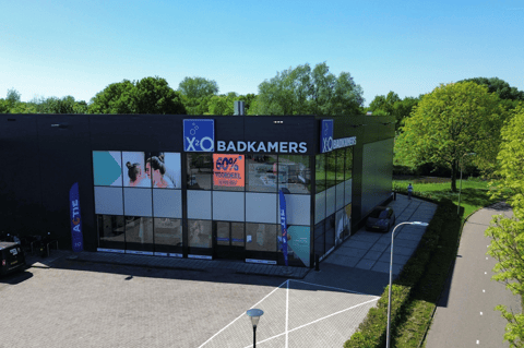 X²O Badkamers winkel met moderne zwarte gevel en grote ramen in een groene omgeving – X²O badkamers