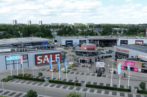 Luchtbeeld van een levendig winkelcentrum met diverse winkels, centrale ontmoetingsplaats en duidelijke promoties zoals “SALE”, ideaal voor een complete shoppingervaring – X²O badkamers