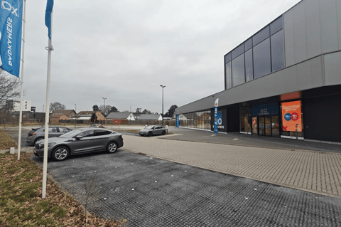 Magasin moderne XO Salles de Bains avec un parking partiellement vide par une journée grise et nuageuse dans un quartier résidentiel calme.
