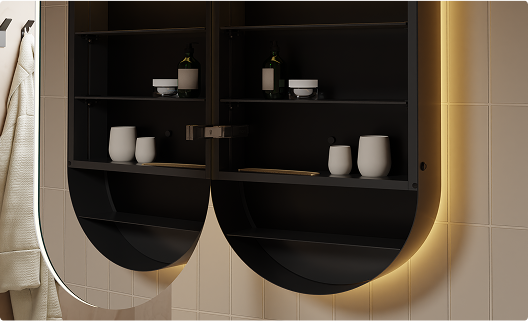 Une armoire de toilette noire ouverte avec formes arrondies, éclairage LED indirect et accessoires tels que flacons et gobelets. Une solution de rangement moderne et haut de gamme de x²o salles de bains.