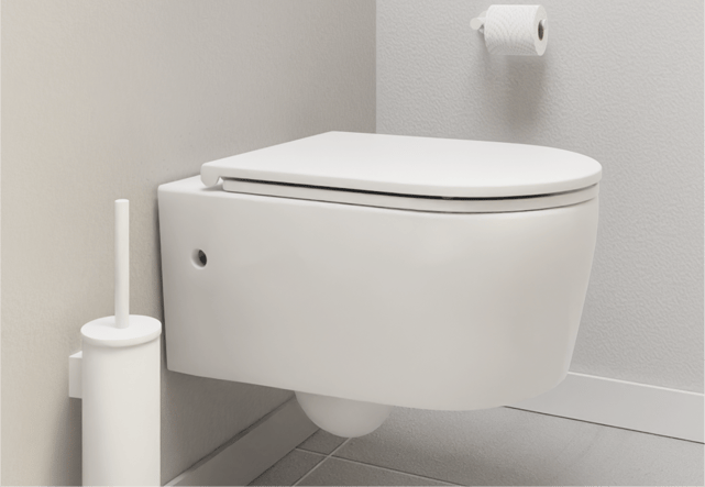 Une toilette suspendue blanche contre un mur gris clair, avec une brosse blanche et un rouleau de papier toilette au mur. Simplicité fonctionnelle de x²o badkamers.