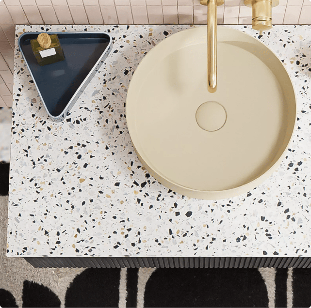 Meuble de salle de bains avec plan en terrazzo, vasque ronde beige et robinet doré