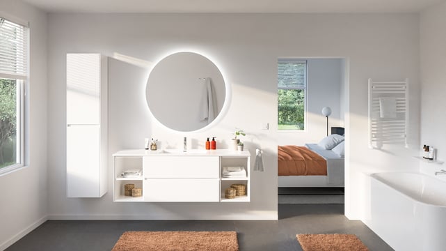 Großer runder Spiegel mit sanfter LED-Beleuchtung in einem offenen weißen Badezimmer mit Blick ins Schlafzimmer.