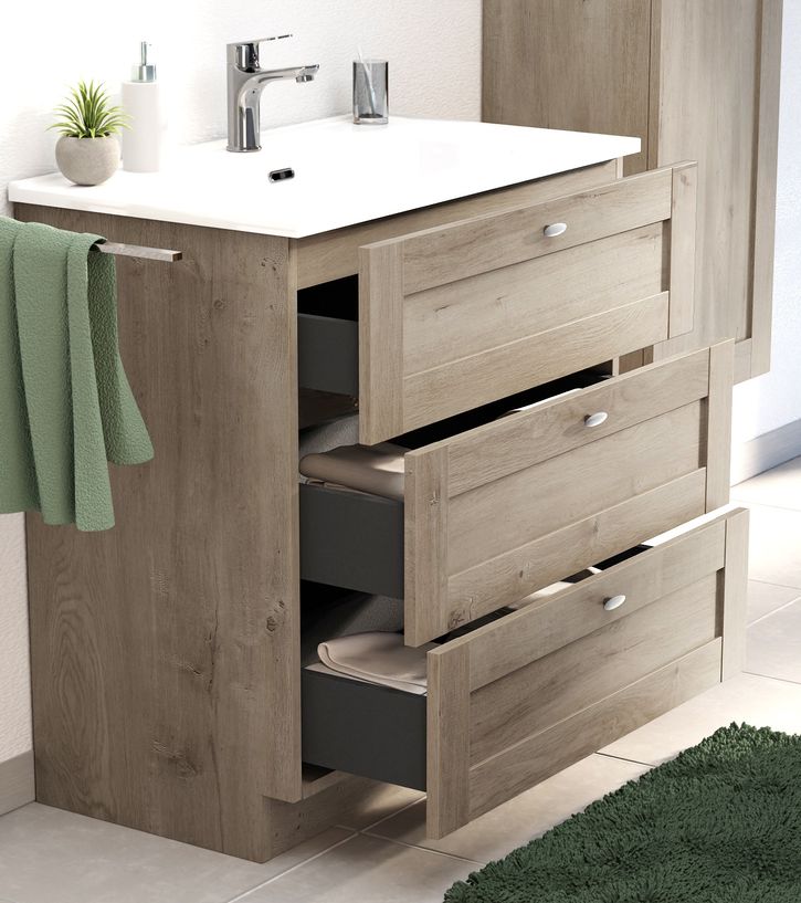 Houten badkamermeubel van x²o badkamers met meerdere open lades waarin handdoeken netjes zijn opgeborgen, afgewerkt met een witte wastafel.