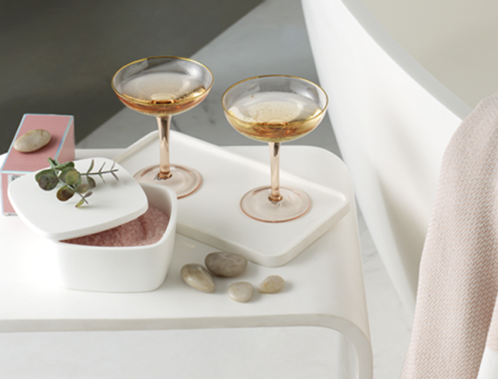 Ambiance chaleureuse de salle de bains avec baignoire îlot, plantes et accessoires doux, présentée comme source d’inspiration cadeau fête des mères chez x²o salles de bains.