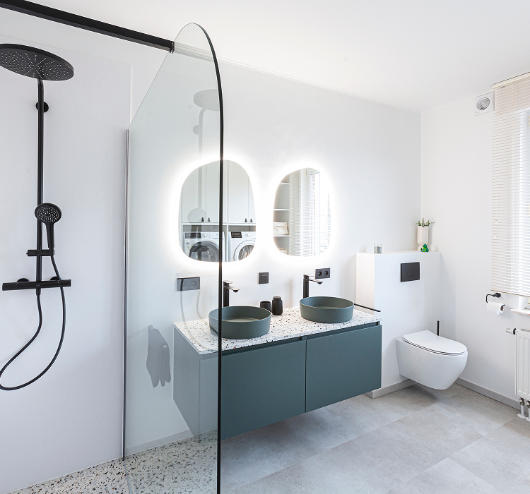 Modernes Badezimmer von x²o Bad mit schwarzer Duschsäule, Glasduschwand, schwebendem Badmöbel in Blaugrün, doppelten grünen Aufsatzbecken, zwei beleuchteten Spiegeln, Hänge-WC und großen Fenstern für viel Tageslicht.