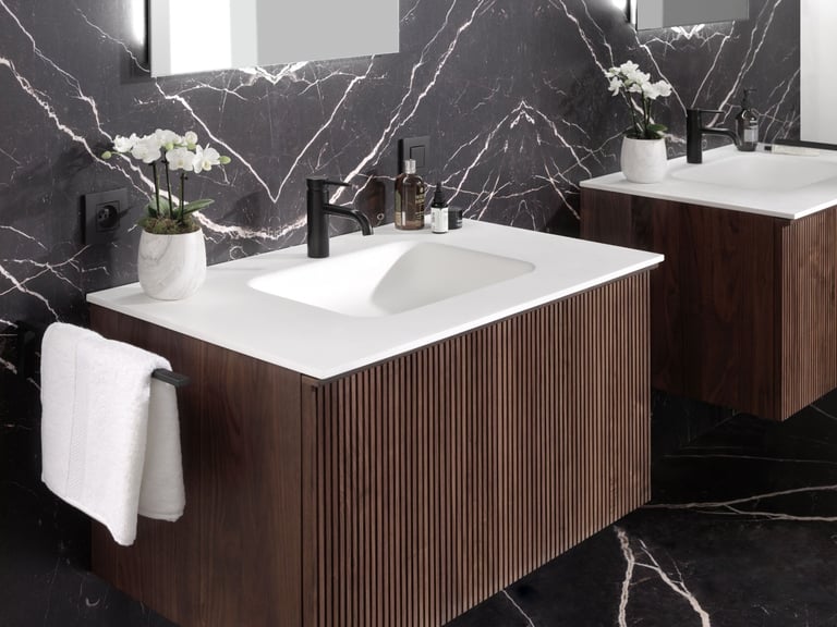 Luxuriöses Badezimmer mit Holz-Waschbeckenmöbeln, schwarzen Marmorwänden und modernen schwarzen Armaturen.