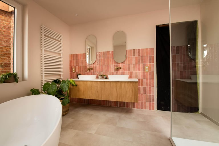 Moderne badkamer met houten wastafelmeubel, dubbele wastafels, tegelwand en glazen douchewand.