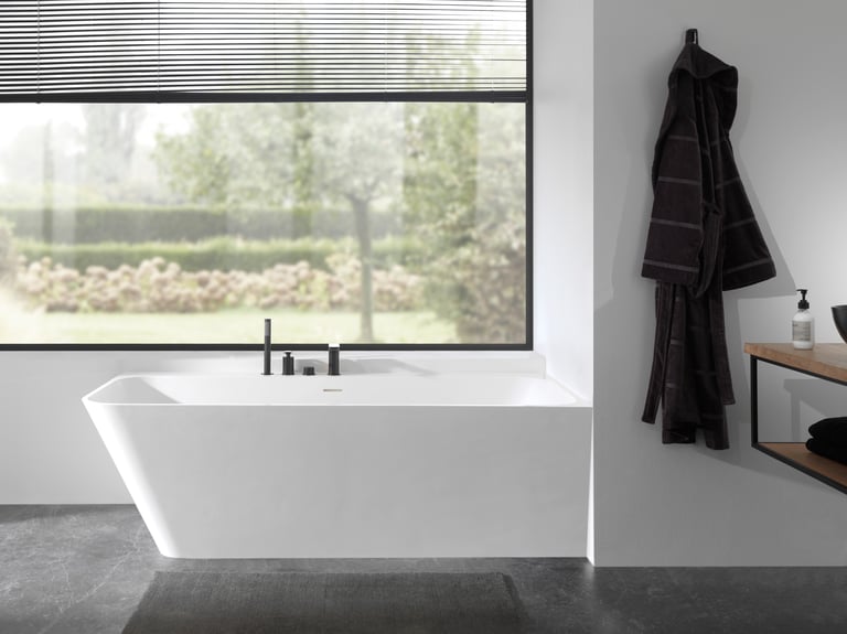 Minimalistische badkamer met Balmani Zigga hoekbad in solid surface van x²o badkamers. Het bad is strak ingebouwd tegen de wand en afgewerkt met een geïntegreerde badrandkraan uit de Blaufoss collectie, wat zorgt voor een sobere en luxueuze uitstraling.
