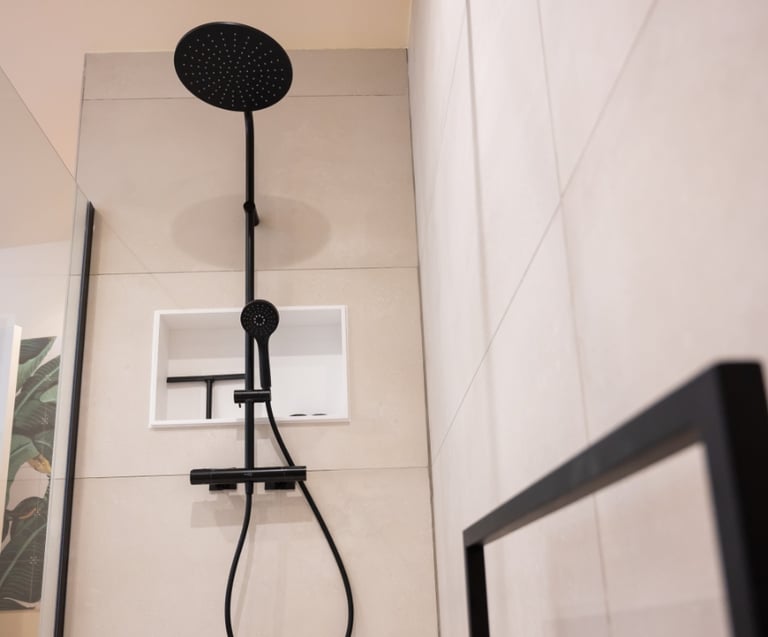 Zwarte inbouwdouche van x²o badkamers met grote ronde regendouche, handdouche en thermostatische kraan, gemonteerd tegen lichte keramische wandtegels. De douche bevindt zich in een moderne badkamer met een minimalistische uitstraling en strakke zwarte accenten.