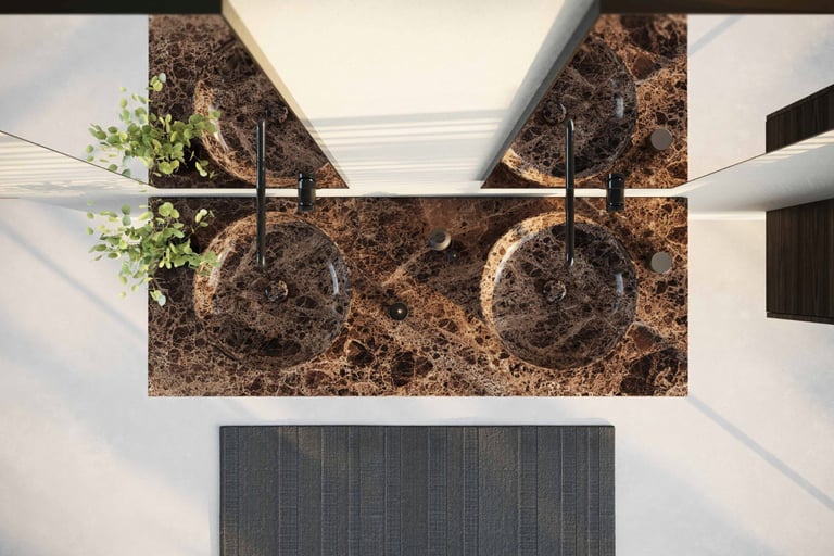 Zicht van bovenaf op een dubbele waskom in donkerbruin marmer met natuurlijke aders, geplaatst op een bijpassend marmeren blad met zwarte kranen en decoratieve planten, gefotografeerd in een moderne badkamer van x²o badkamers.