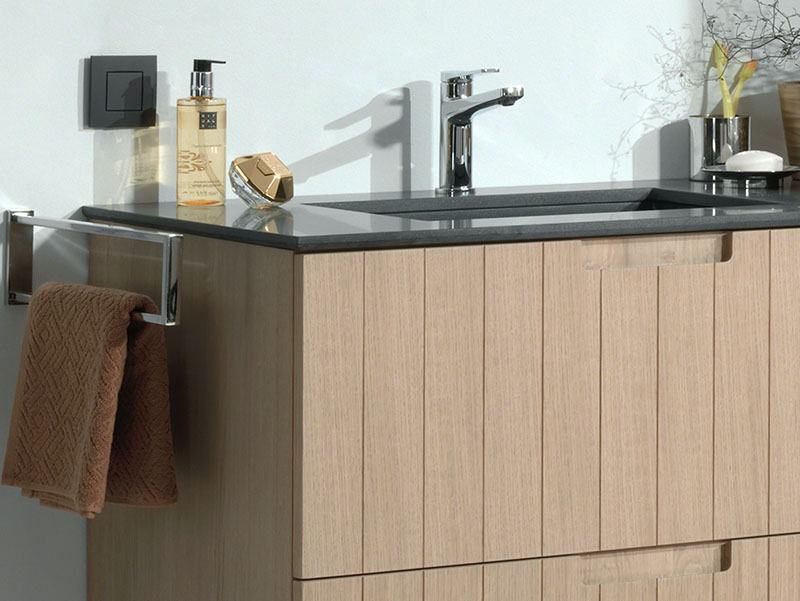 Badkamer met houten wastafelmeubel, dubbele zwarte waskommen en een grote spiegel tegen een donkere muur.