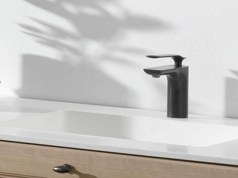 Wastafel met wit blad en minimalistische zwarte kraan op een houten meubel.