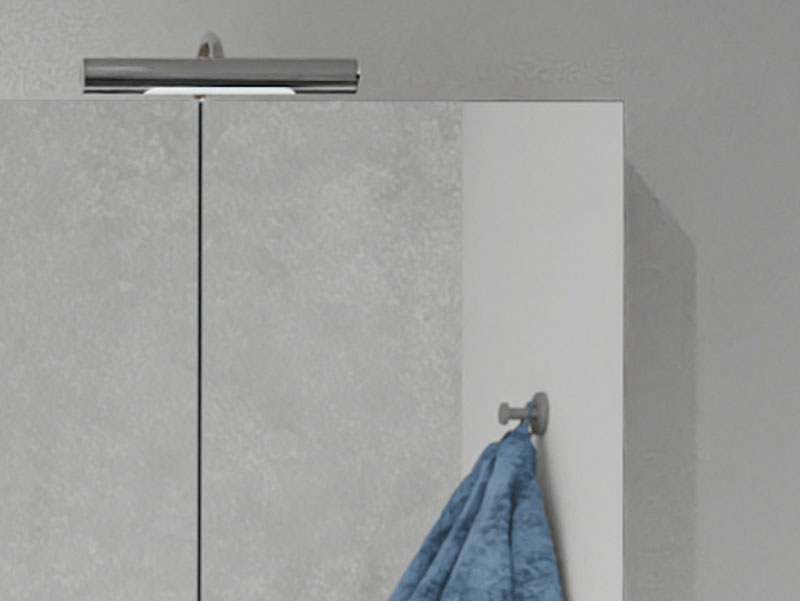 Detail van een spiegelkast met verlichting en een handdoek aan een haakje ernaast.
