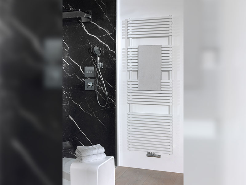 Badkamer met zwarte marmeren douchewand, moderne douchekraan en witte handdoekradiator met handdoek.