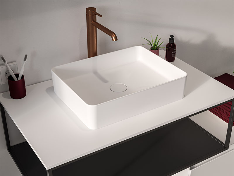 Witte rechthoekige opzetwaskom op een modern badkamermeubel met bronzen kraan en minimalistisch design.