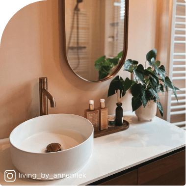 Salle de bains moderne avec vasque ronde, robinet en bronze et détails en bois pour une ambiance naturelle.